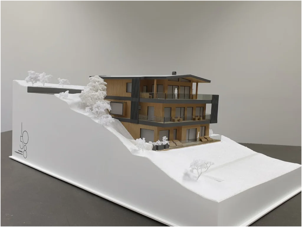 Architekturmodell eines mehrgeschossigen Wohngebäudes in Hanglage mit Terrassen, Balkonen und abstrahierter Geländedarstellung