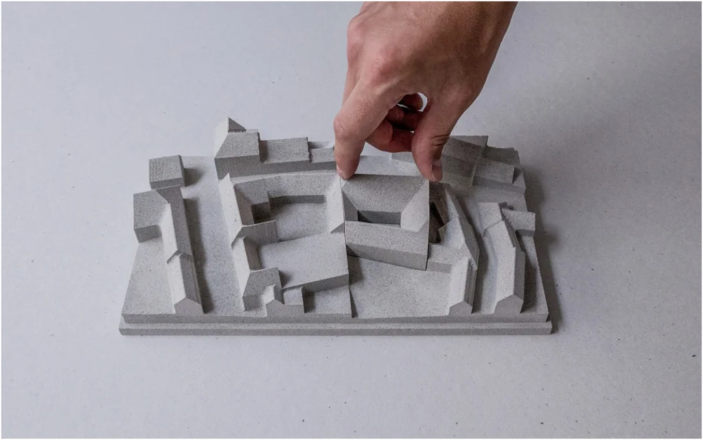 Arbeitsprozess an einem Architekturmodell: Hand platziert Volumenkörper in einer konzeptionellen Massenstudie zur städtebaulichen Analyse
