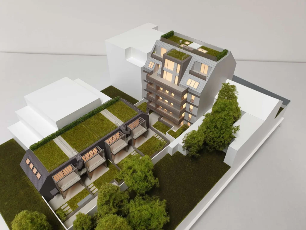Immobilienmodell mit integrierter Beleuchtung, Darstellung eines Wohngebäudes mit Umgebungsbebauung, Grünflächen und Maßstabsvergleich im städtebaulichen Kontext