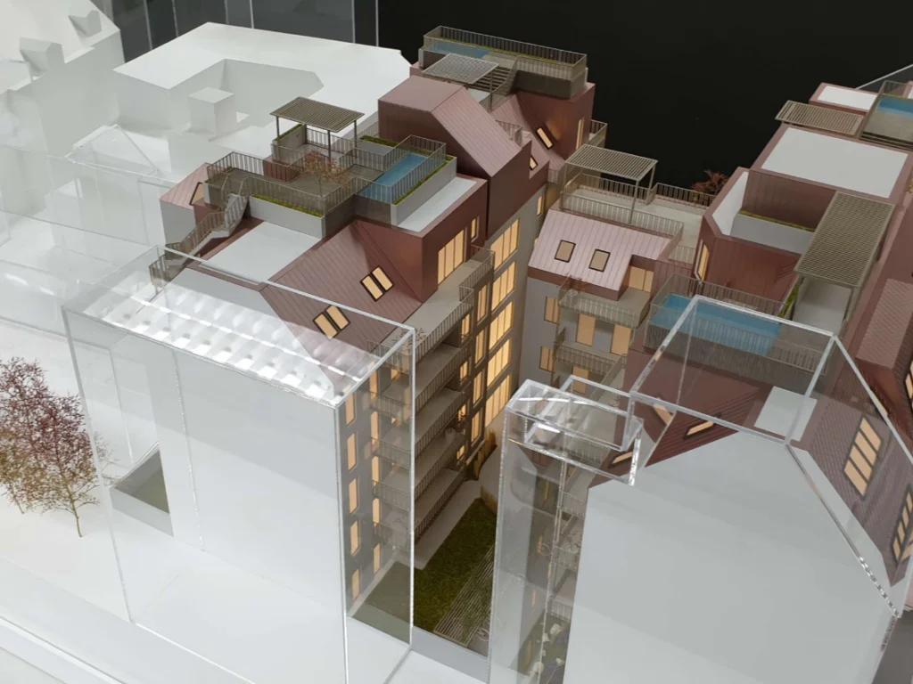 Immobilienmodell mit beleuchteter Wohnbebauung und transparenter Darstellung der Umgebungsgebäude, Kombination aus detaillierter Architektur, Dachterrassen und abstrahiertem städtebaulichem Kontext