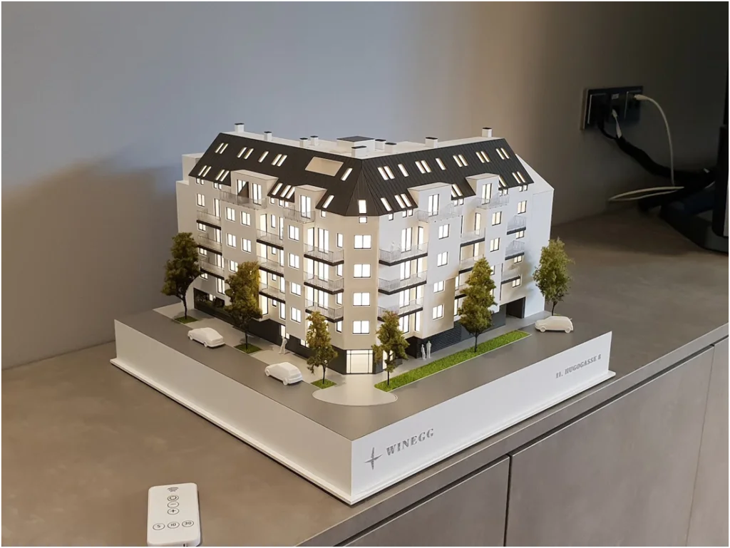 Immobilienmodell im Maßstab 1:100 – detailliertes Architekturmodell eines Wohngebäudes mit Balkonen und Stadtumfeld
