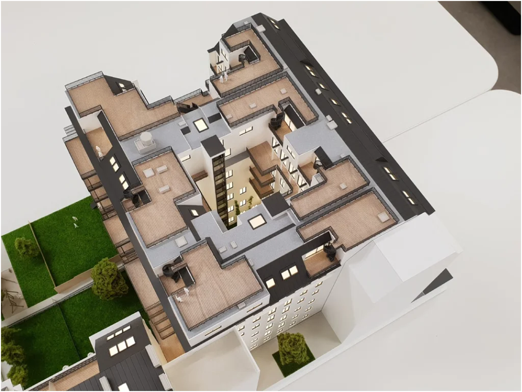 Immobilienmodell im Maßstab 1:100 – Architekturmodell eines Wohnbauprojekts mit Innenhof, Dachterrassen und Grünflächen
