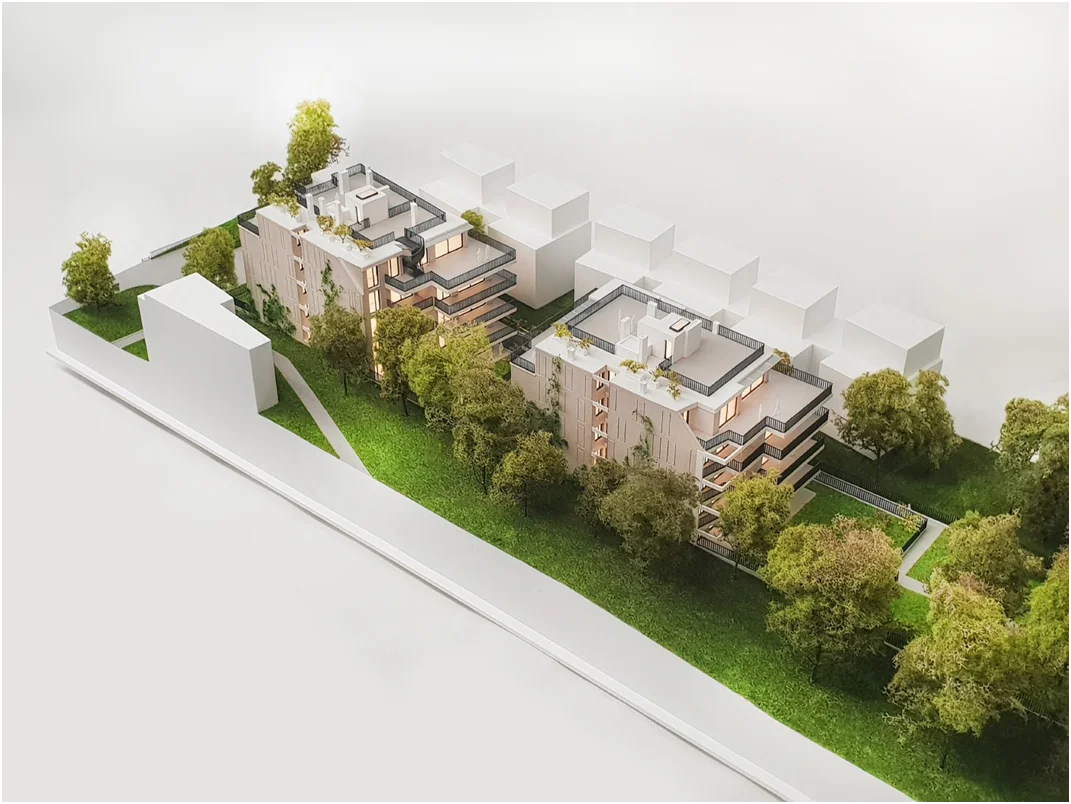Architekturmodell einer modernen Neubau-Wohnanlage im Maßstab 1:100 mit mehreren Gebäuden und Grünflächen
