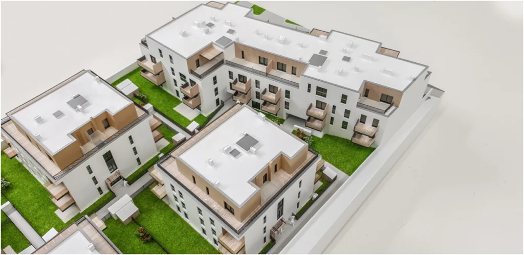 Vogelperspektive auf ein Quartiersmodell eines Wohnprojekts mit mehreren Gebäuden, vollfarbiges Architekturmodell mit Grünflächen, Wegen und Innenhöfen