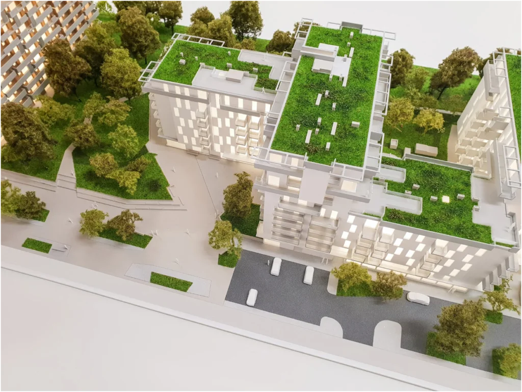 Vogelperspektive auf ein Quartiersmodell eines Wohnprojekts mit mehreren Gebäuden und begrünten Dachflächen, vollfarbiges Architekturmodell mit Außenanlagen und Wegen