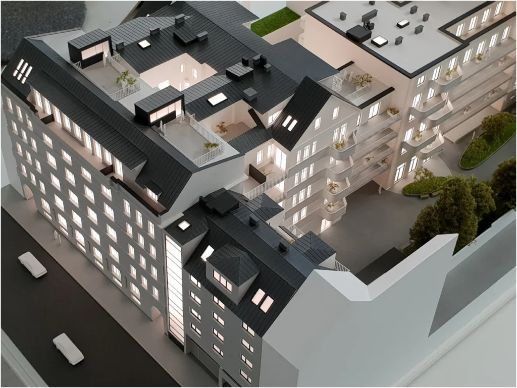 Vogelperspektive auf ein beleuchtetes Wohnquartiermodell mit mehrgeschossigen Gebäuden, Architekturmodell mit Innenhof, Balkonen und Dachterrassen
