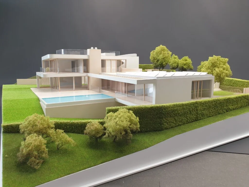 Vollfarbiges Architekturmodell einer modernen Flachbau-Villa mit weitläufiger Grünanlage und Swimmingpool.