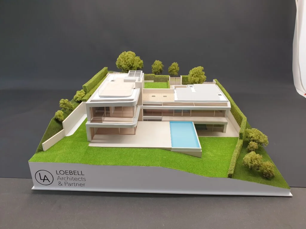 Vollfarbiges Architekturmodell eines modernen Mehrfamilienhauses mit mehreren Wohneinheiten, Balkonen und realistischer Begrünung.