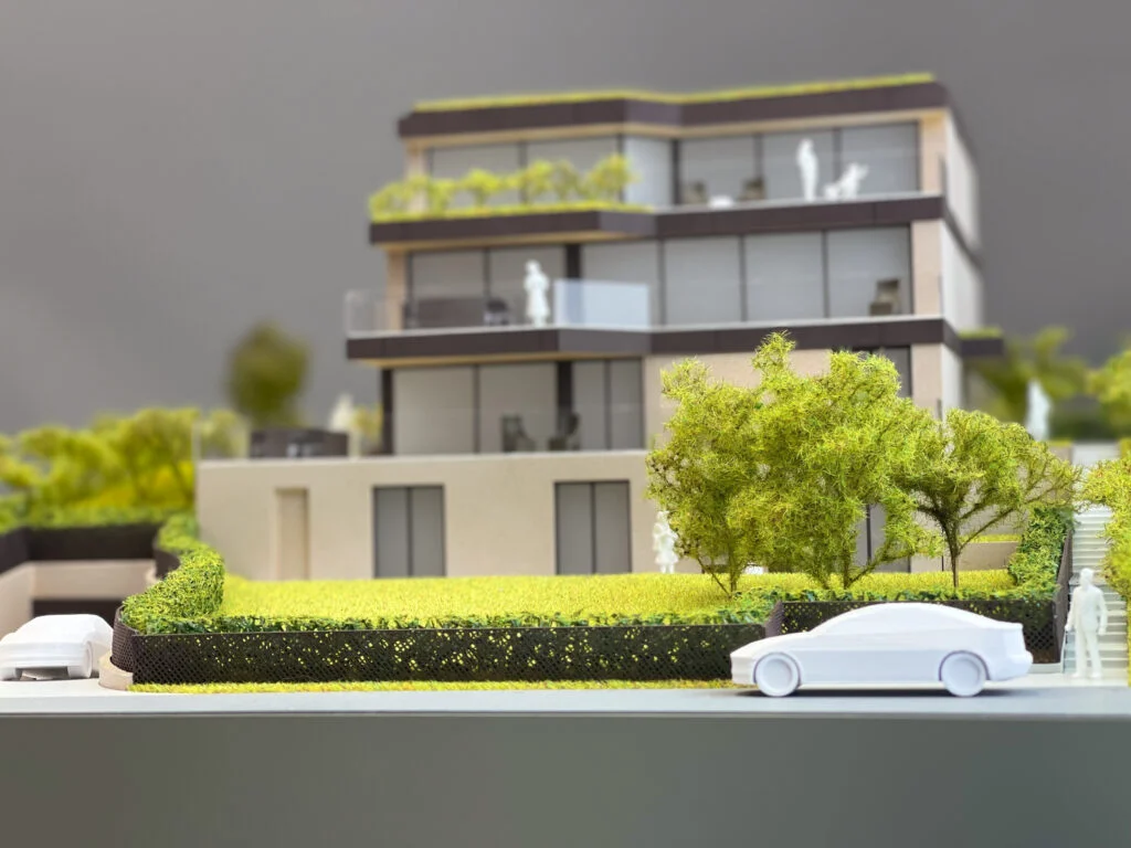 Vollfarbiges Architekturmodell eines mehrgeschossigen, modernen Wohn- oder Geschäftshauses mit Dachbegrünung und Terrassen.